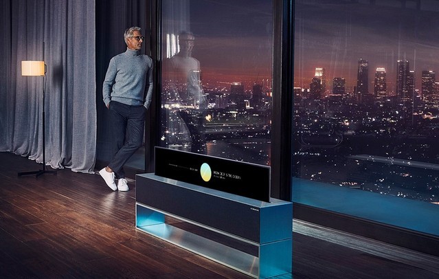 Egy frfi keresztbe tett lbakkal egy tmls szken l, egy LG SIGNATURE felcsavarhat OLED TV fel fordulva.